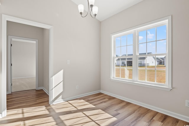 spare room featuring a notable chandelier and light hardwood / wood-style flooring