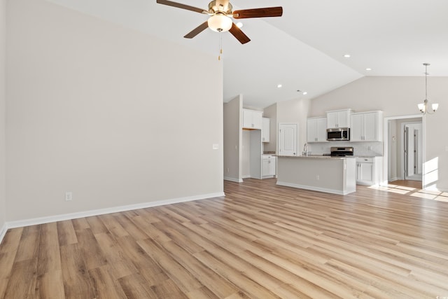 unfurnished living room with high vaulted ceiling, light hardwood / wood-style floors, and ceiling fan with notable chandelier