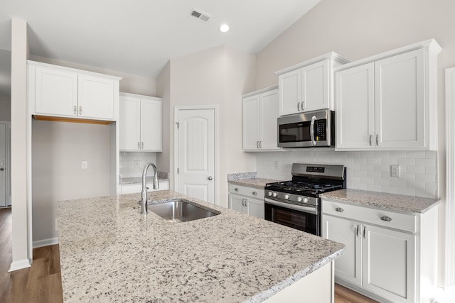 kitchen featuring white cabinetry, sink, stainless steel appliances, and a center island with sink