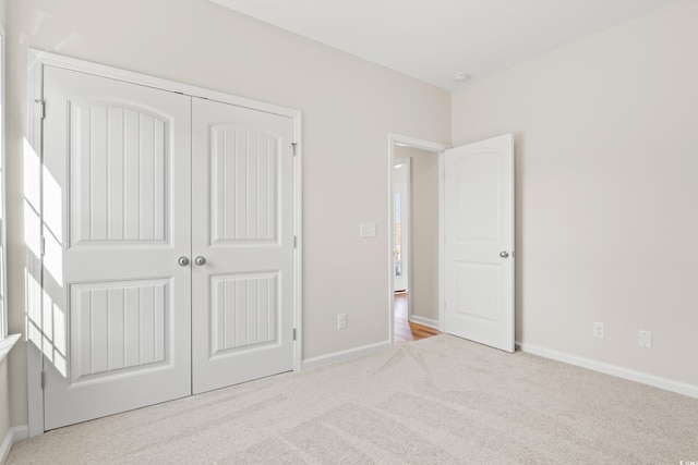 unfurnished bedroom with a closet and light colored carpet