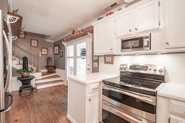 kitchen featuring tasteful backsplash, white cabinets, light wood-type flooring, and stainless steel appliances