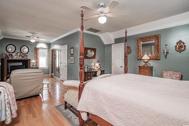 bedroom with ceiling fan, light hardwood / wood-style flooring, a textured ceiling, and ornamental molding