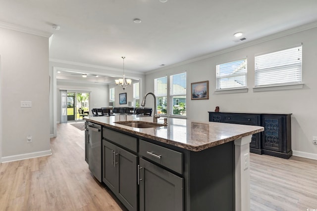 kitchen with light hardwood / wood-style flooring, dishwasher, sink, a kitchen island with sink, and dark stone countertops