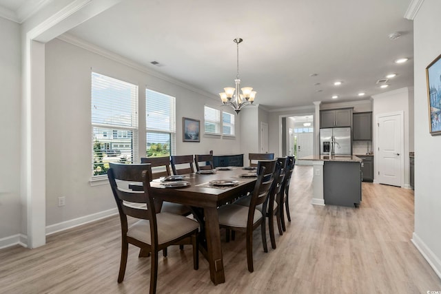 dining space with crown molding, an inviting chandelier, and light hardwood / wood-style flooring