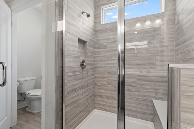 bathroom with toilet, a shower with door, and hardwood / wood-style flooring