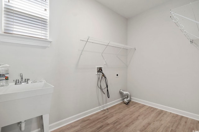 clothes washing area with sink, light hardwood / wood-style floors, hookup for a washing machine, and hookup for an electric dryer