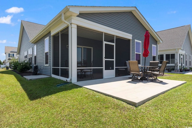 rear view of property featuring a patio area, a sunroom, and a lawn