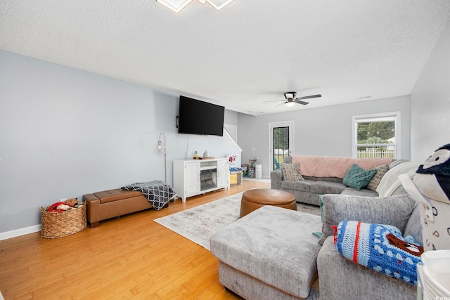 living room with a textured ceiling, wood-type flooring, and ceiling fan