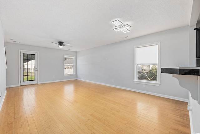 unfurnished living room featuring light wood-style floors, ceiling fan, baseboards, and a textured ceiling