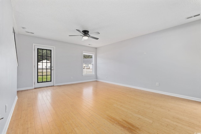 empty room with baseboards, visible vents, ceiling fan, a textured ceiling, and light wood-type flooring