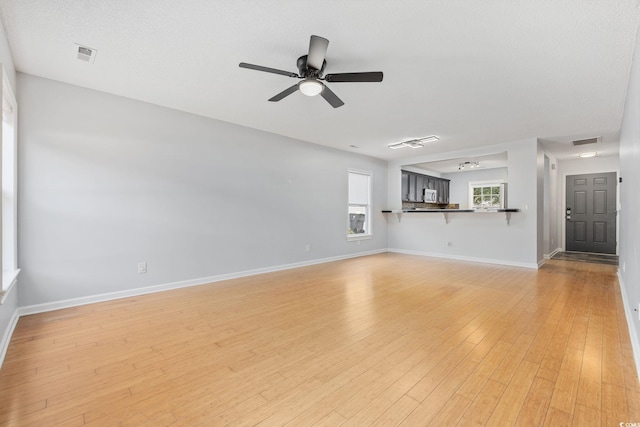 unfurnished living room with a ceiling fan, light wood-style flooring, visible vents, and baseboards