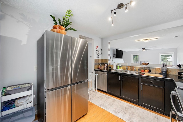 kitchen featuring sink, a textured ceiling, light hardwood / wood-style floors, stainless steel appliances, and ceiling fan