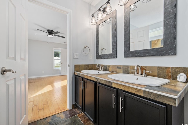 bathroom with double vanity, stone finish flooring, baseboards, and a sink