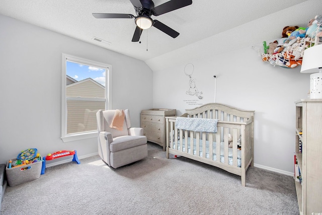 bedroom featuring a textured ceiling, carpet floors, ceiling fan, lofted ceiling, and a nursery area