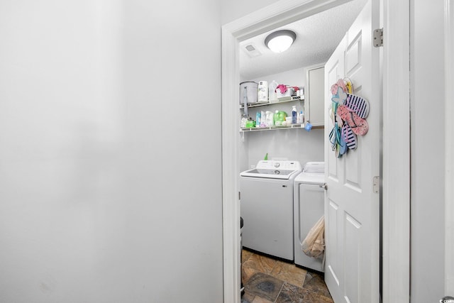 clothes washing area with a textured ceiling and washer and clothes dryer