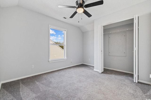 unfurnished bedroom featuring a textured ceiling, visible vents, baseboards, vaulted ceiling, and carpet