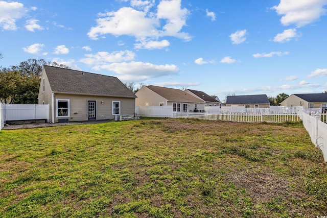 back of house featuring a lawn and a fenced backyard