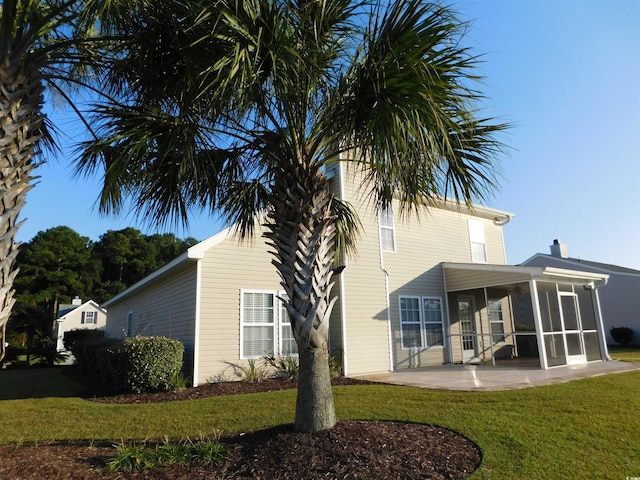 rear view of house featuring a lawn, a sunroom, and a patio