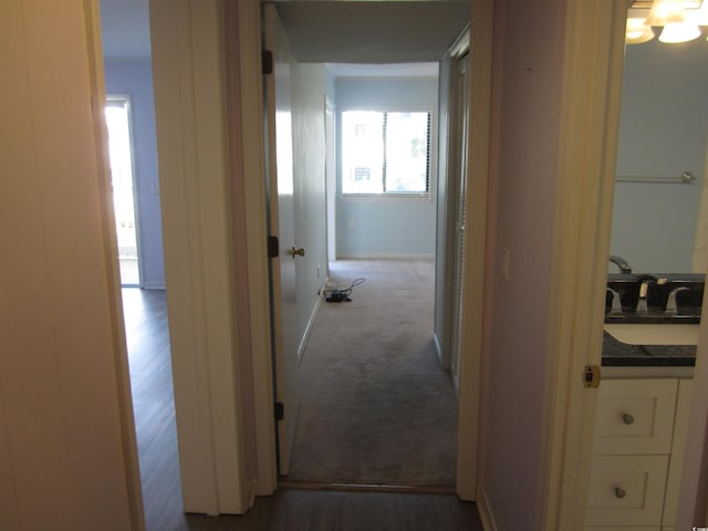 corridor with sink and dark colored carpet