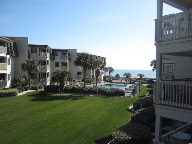 view of property's community featuring a water view, a yard, and a swimming pool