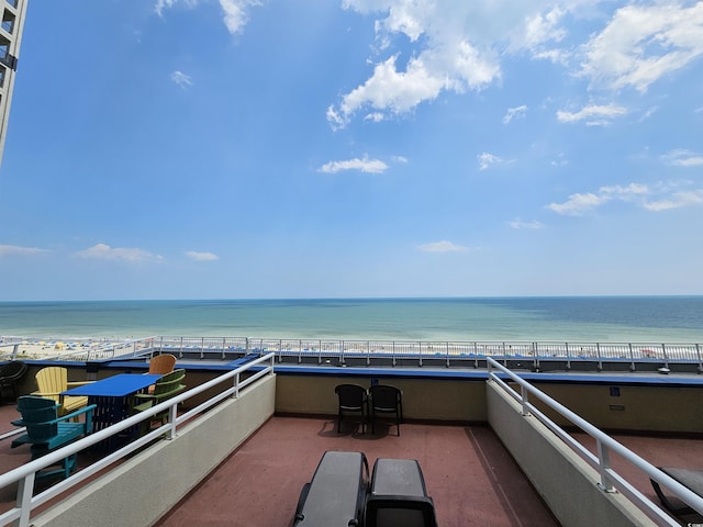 view of patio / terrace with a water view, a beach view, and a balcony