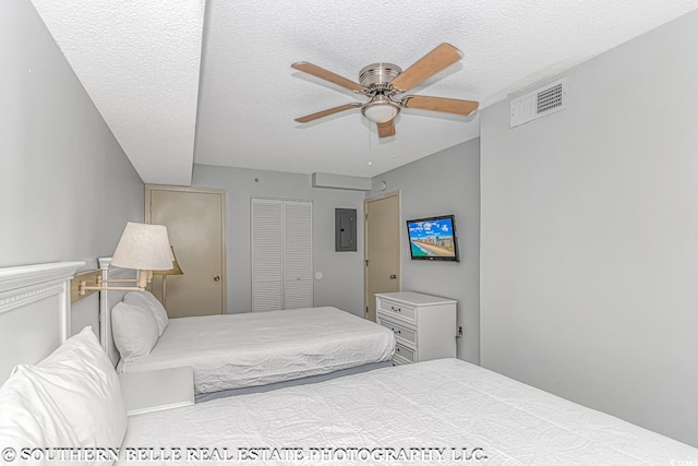 bedroom with a textured ceiling, electric panel, ceiling fan, and a closet