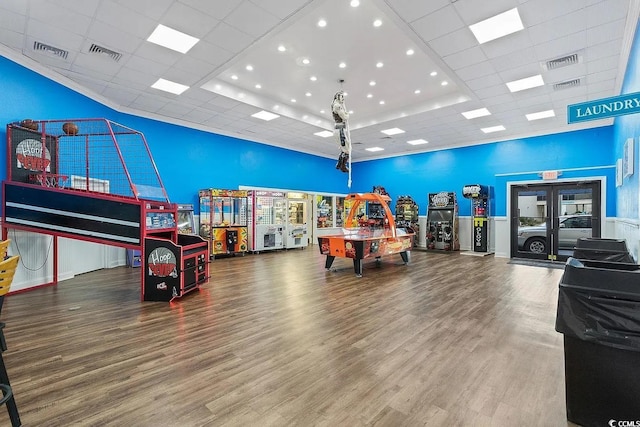 game room with a towering ceiling, a raised ceiling, and hardwood / wood-style floors