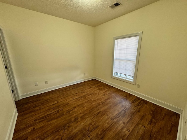 empty room featuring dark hardwood / wood-style flooring and a textured ceiling