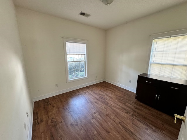 empty room with a textured ceiling and dark hardwood / wood-style flooring