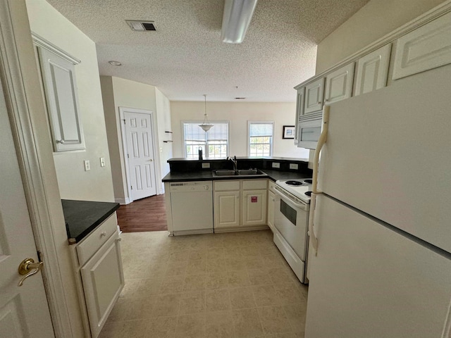 kitchen featuring a textured ceiling, white appliances, pendant lighting, kitchen peninsula, and sink