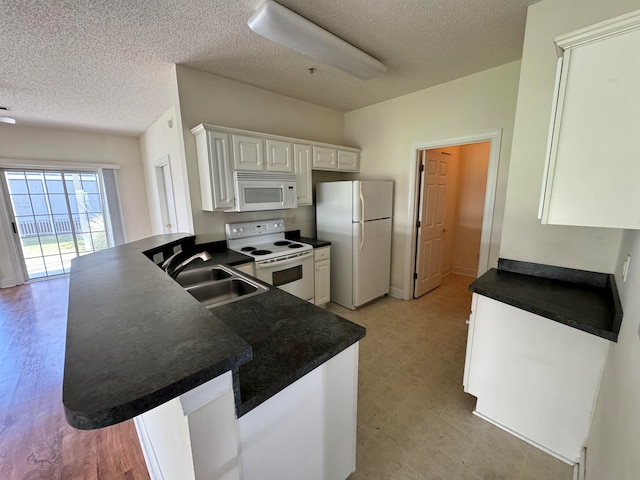 kitchen featuring light wood-type flooring, white appliances, kitchen peninsula, and sink