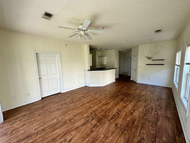 unfurnished living room with a textured ceiling, ceiling fan, and dark hardwood / wood-style floors