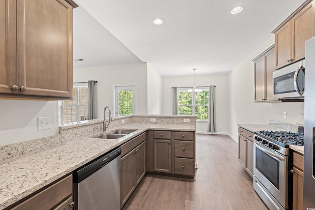 kitchen featuring sink, stainless steel appliances, kitchen peninsula, and light hardwood / wood-style flooring