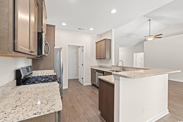 kitchen with appliances with stainless steel finishes, light hardwood / wood-style flooring, ceiling fan, kitchen peninsula, and lofted ceiling