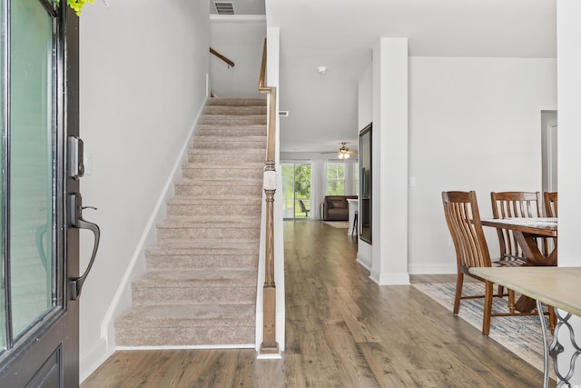 staircase with hardwood / wood-style flooring and ceiling fan