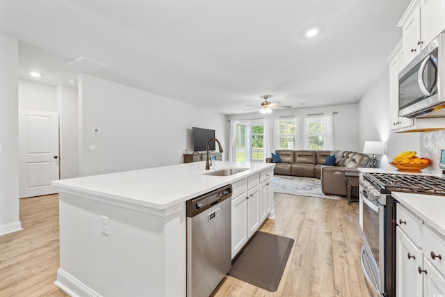 kitchen with sink, an island with sink, light hardwood / wood-style floors, ceiling fan, and stainless steel appliances