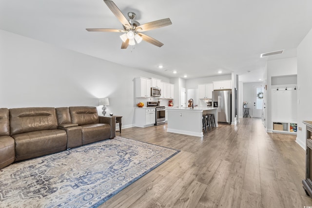 living room featuring sink, light hardwood / wood-style flooring, and ceiling fan