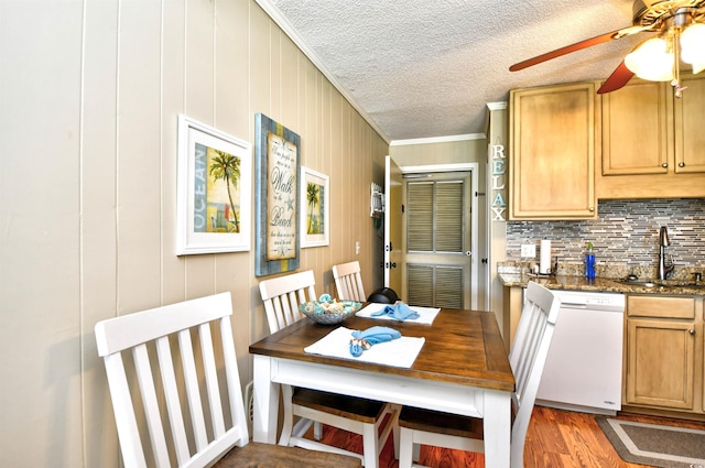 dining area with ceiling fan, wood walls, ornamental molding, sink, and dark hardwood / wood-style flooring