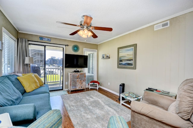 living room featuring ceiling fan, hardwood / wood-style flooring, ornamental molding, and a textured ceiling