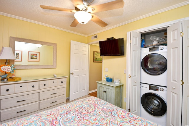 bedroom with a textured ceiling, crown molding, stacked washer and dryer, and ceiling fan