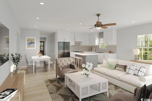 living room featuring ceiling fan, sink, and light wood-type flooring