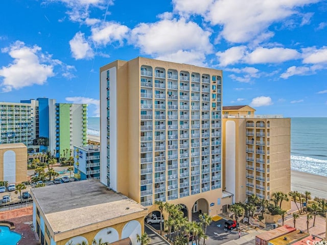 view of building exterior featuring a water view and a beach view