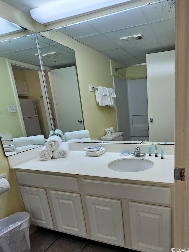 bathroom with a drop ceiling, tile patterned flooring, and vanity