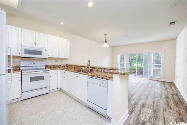 kitchen with kitchen peninsula, white appliances, stone countertops, and sink