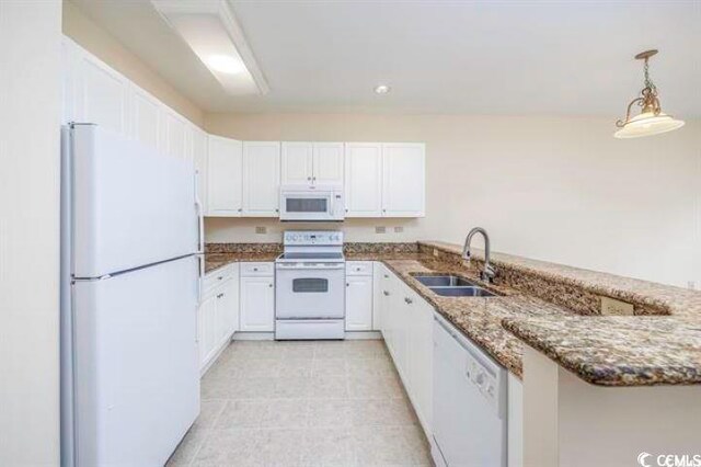 kitchen with sink, white appliances, dark stone countertops, and kitchen peninsula