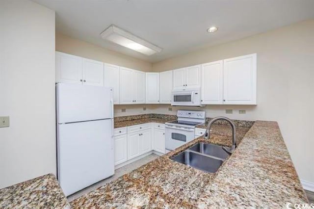 kitchen with stone counters, sink, white appliances, and white cabinets