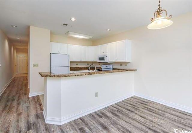 kitchen with hardwood / wood-style flooring, white cabinets, kitchen peninsula, and white appliances