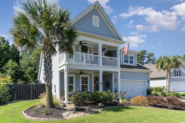 view of front of property featuring a balcony, ceiling fan, a garage, and a front lawn