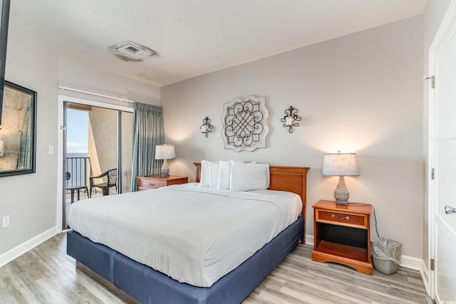 bedroom with access to outside, wood finished floors, visible vents, and baseboards