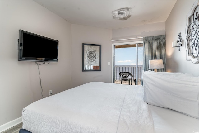 bedroom with baseboards, wood finished floors, and access to exterior